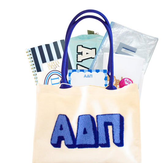 ADPi tote bag full of items with the greek letters for bid day, initiation, and big sister little sister reveals