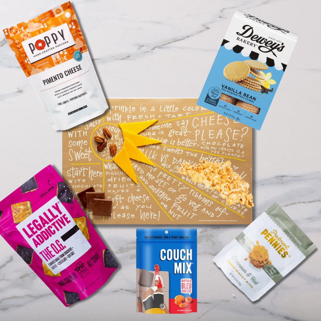 Top view of Sunburst Charcuterie Cheat Sheet surrounded by NC-made gourmet snacks like popcorn, cookies, and cheese wafers ready to create a delicious charcuterie board.