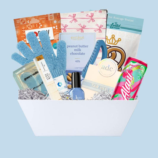 UNC Chapel Hill gift basket full of Carolina blue gifts for girls who enjoy self care, including a Tar Heels game day bracelet, UNC chocolates, cosmetic items, and made in North Carolina snacks