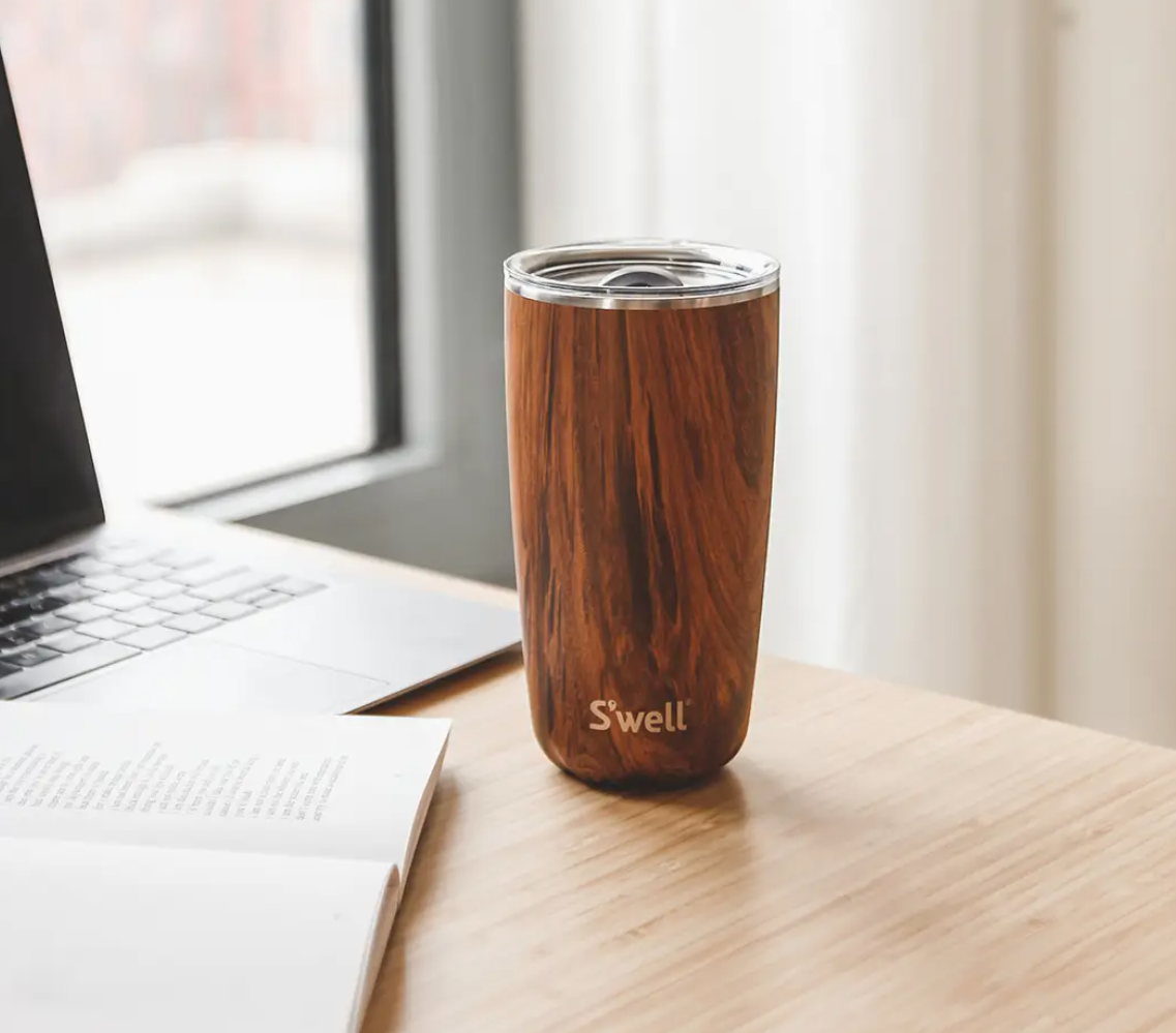 Wooden tumbler with 'Swell' branding on a desk next to a laptop. Great gift for men who have everything