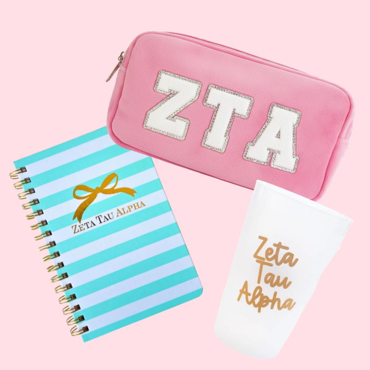 Pink pouch, striped notebook, and white card with 'Zeta Tau Alpha' on a pink background