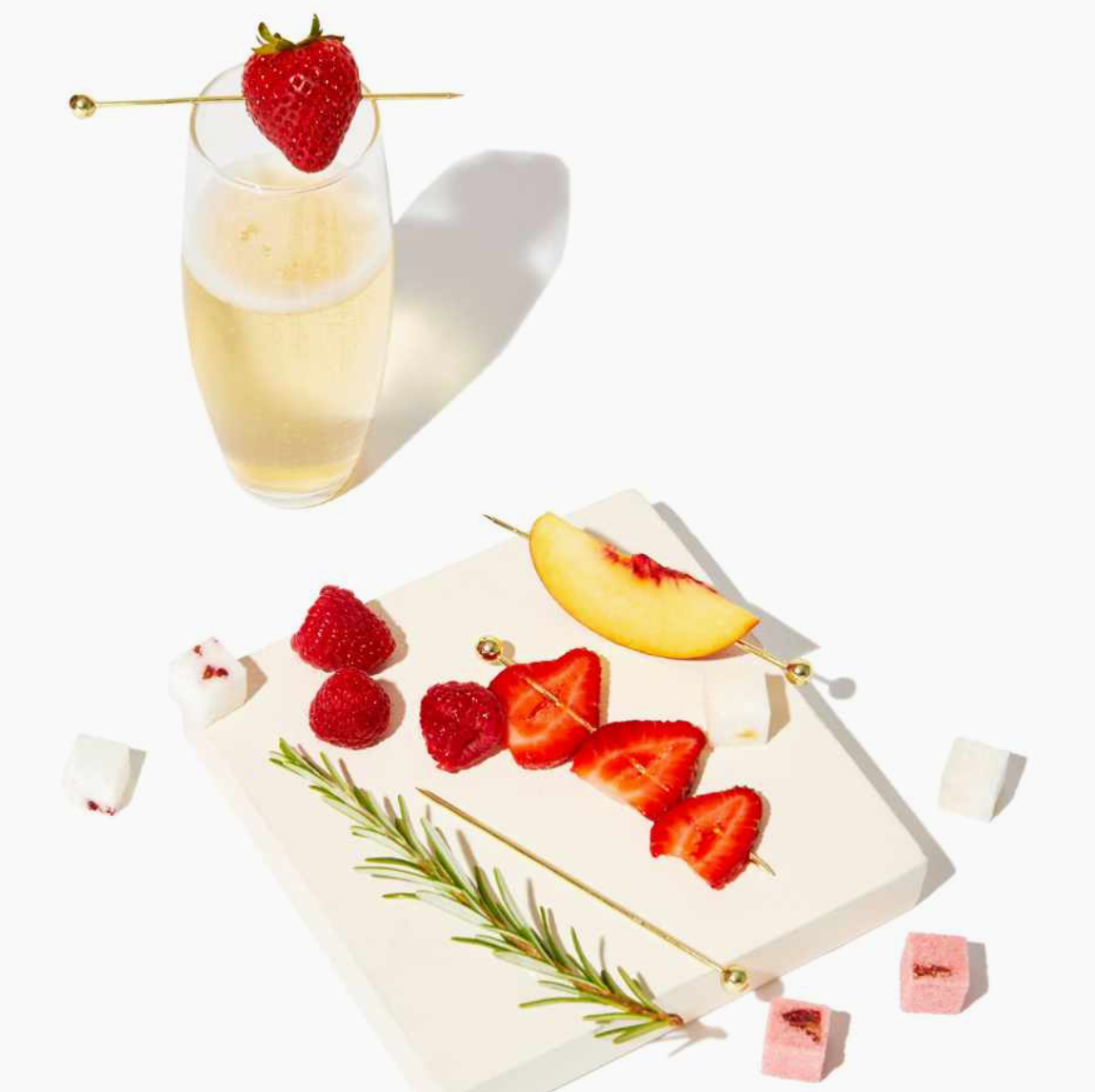 Elegant lifestyle image of fresh strawberries speared on gold cocktail picks resting on a champagne glass, highlighting the stylish bar accessories included in the Men’s Old Fashioned Gift Box.