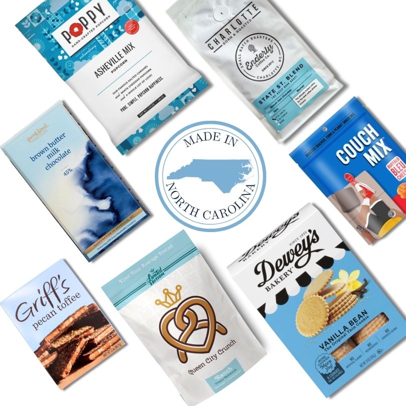 Flat lay of gourmet food products included in the Carolina Blue Deluxe Gift Basket, featuring NC-made snacks and a central "Made in North Carolina" icon.