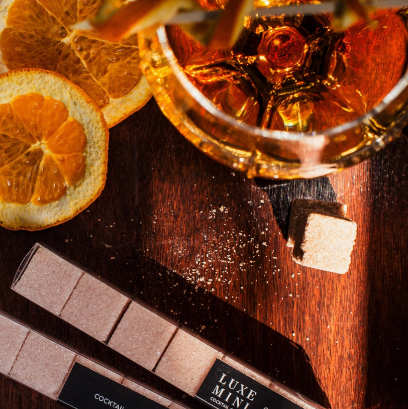 Top-down lifestyle image of an Old Fashioned cocktail beside Old Fashioned Luxe Mini Sugar Cubes, showcasing the elevated ingredients included in the Men’s Old Fashioned Gift Box.