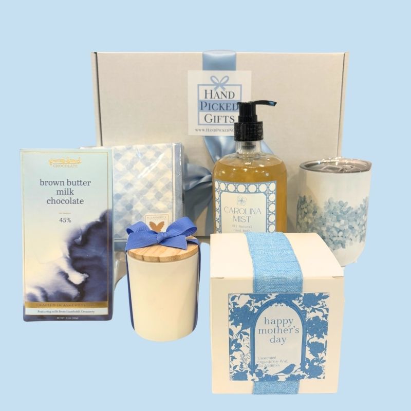 All items from the luxury Mother's Day gift box displayed in front of the box, including NC-made chocolate, hand soap, candle, floral tumbler, and gingham napkins.