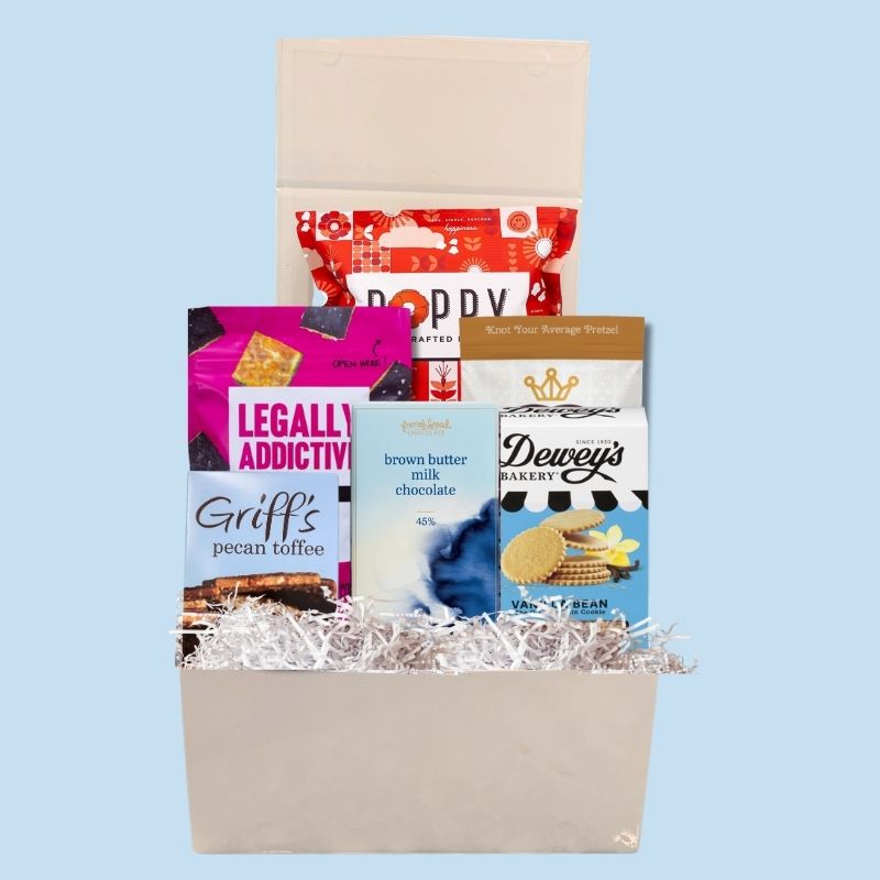Open branded magnetic gift box filled with North Carolina-made gourmet sweet treats, including chocolate, popcorn, cookies, and pretzels