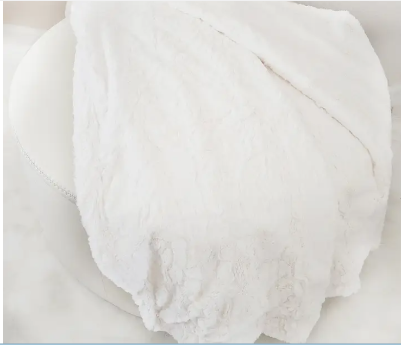 A luxurious faux fur lap blanket draped across a chair, highlighting its soft, reversible sides and inviting, cozy appeal.