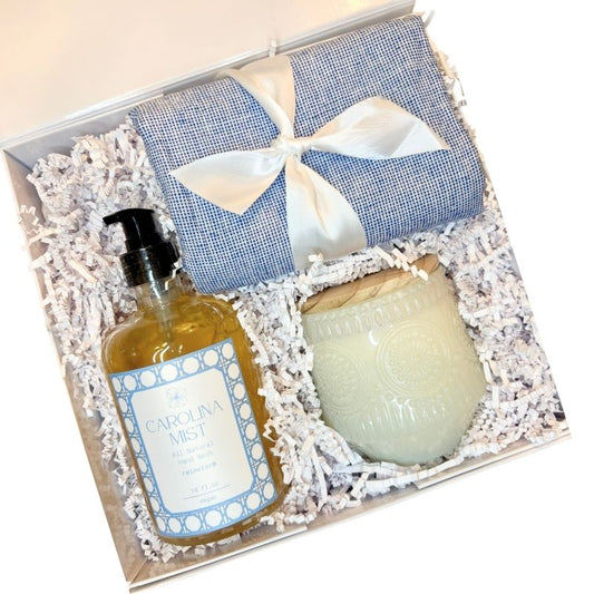 Luxury gift box perfect for housewarming or new home gift. Contains blue dish towel, luxury hand soap  with Carolina Mist label, and unscented decorative candle