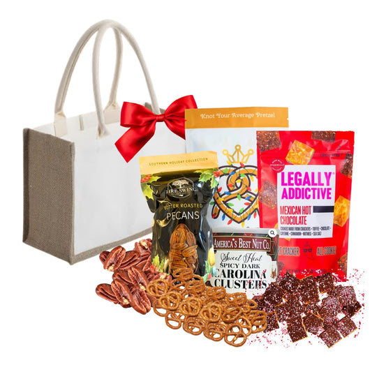Assorted snack items including pretzels, nuts, and chocolate with a gift bag and bow on a white background.