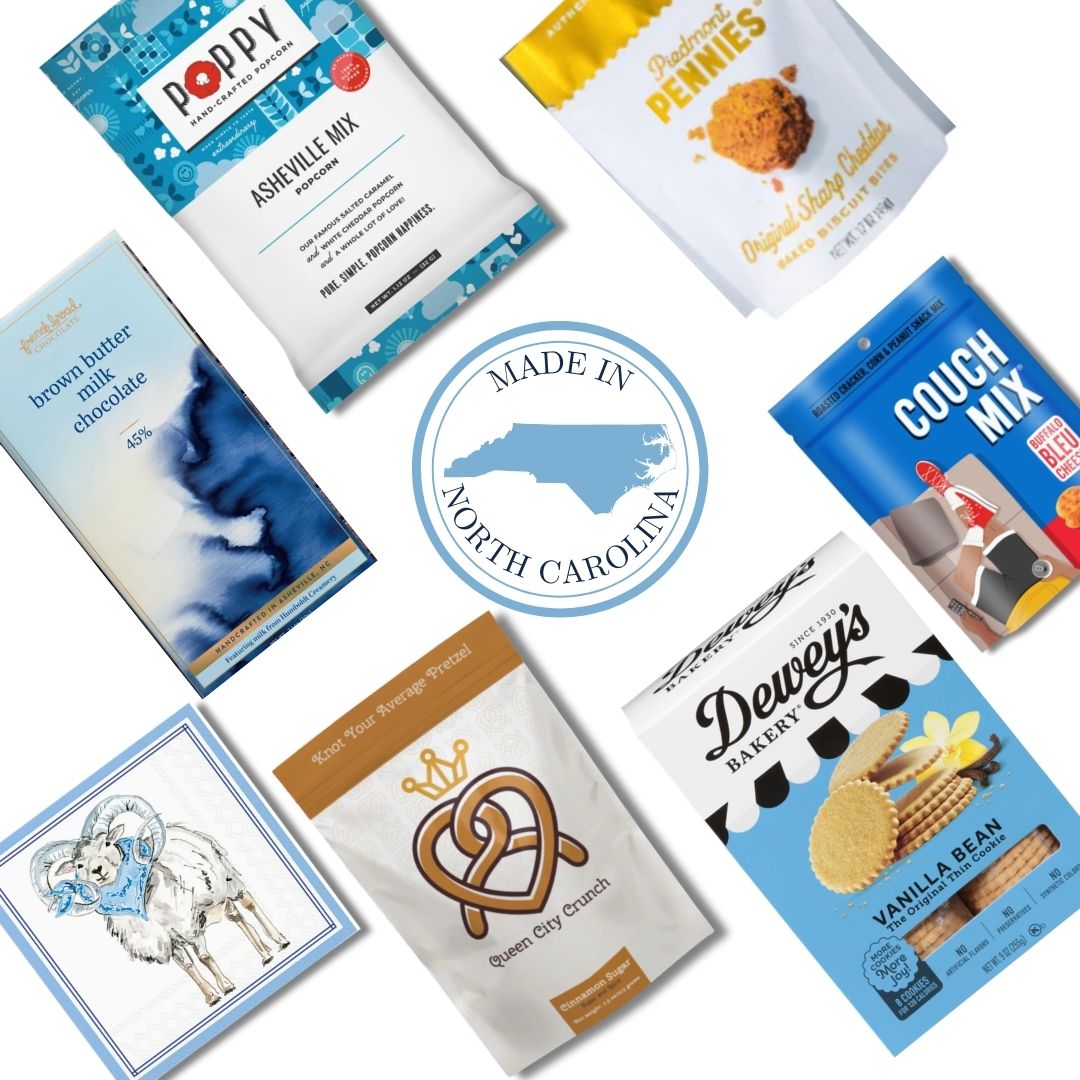 Flat lay of gourmet food products included in the Carolina Blue Deluxe Gift Basket, featuring NC-made snacks and a central "Made in North Carolina" icon.