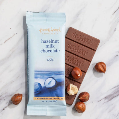 Hazelnut milk chocolate bar  made in North Carolina by French Broad Chocolate in Asheville with packaging on a marble surface