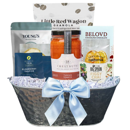Gift basket with various healthy products including granola, tea, and chocolate, tied with a blue ribbon.
