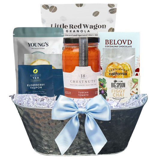 Gift basket with various healthy products including granola, tea, and chocolate, tied with a blue ribbon.
