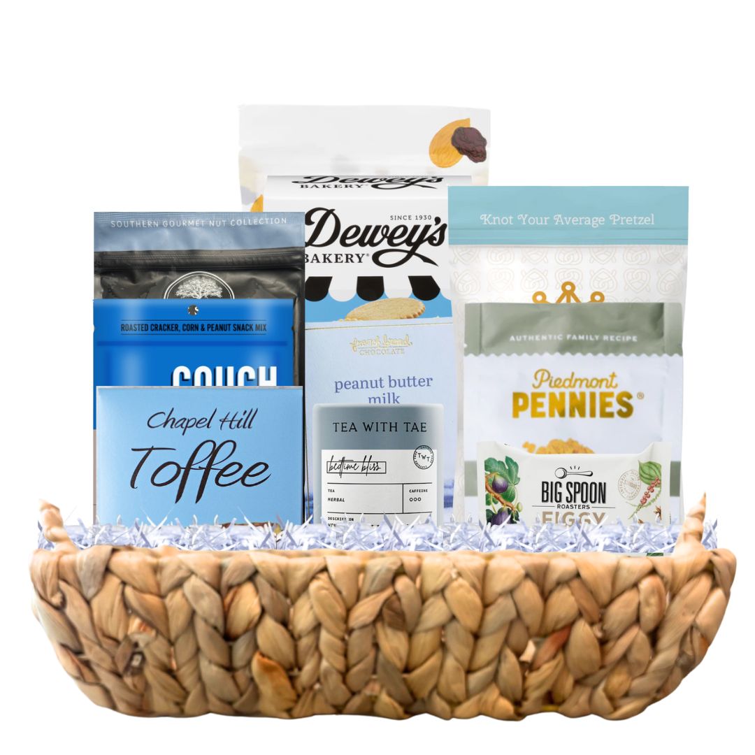 Luxury winter gift basket arranged in a woven hyacinth tray with gourmet North Carolina snacks, artisan coffee, chocolate, popcorn, and toffee in blue and white packaging suitable for Hannukah.