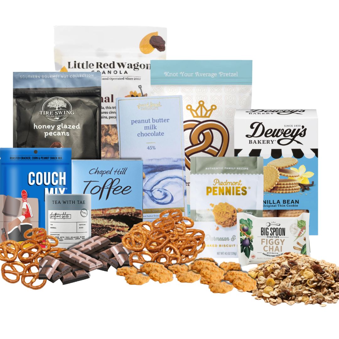 Winter Luxe Gourmet gift basket contents displayed on a kitchen counter  with North Carolina artisan snacks, popcorn, pretzels, chocolate, toffee, coffee, and hot chocolate arranged neatly with piles of each treat in front of its packaging.