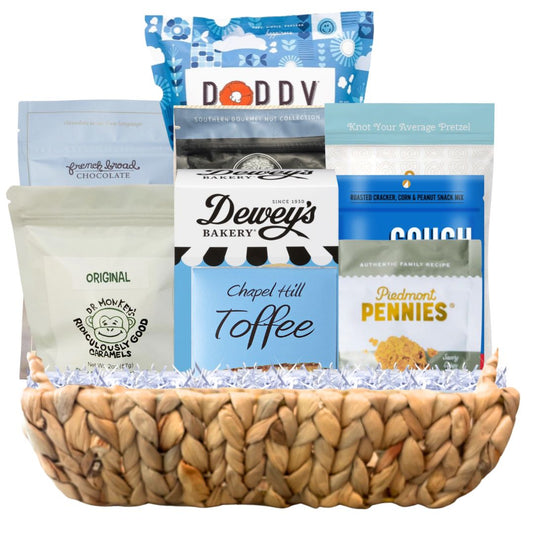 Luxury winter gift basket arranged in a woven hyacinth tray with gourmet North Carolina snacks, artisan coffee, chocolate, popcorn, and toffee in blue and white packaging suitable for Hannukah.