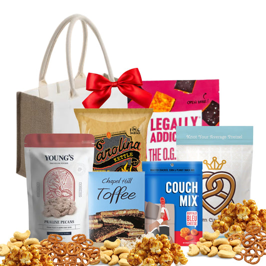 Assorted snack items including pretzels, nuts, and chocolate with a gift bag and bow on a white background.