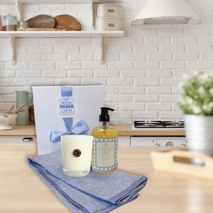 Kitchen counter with a Dogwood candle, bottle of Carolina Mist soap, and gift box on a blue towel.