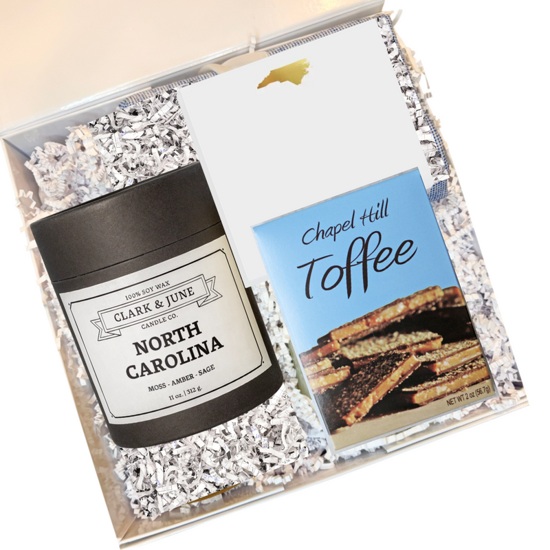 Gift set with a candle labeled 'North Carolina', a NC notepad, and a box of 'Chapel Hill Toffee' in a decorative box.