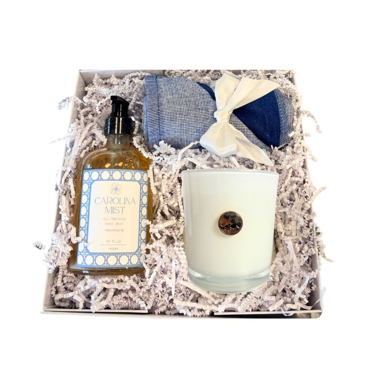 Gift set with a bottle, candle, and eye mask in a box with shredded paper
