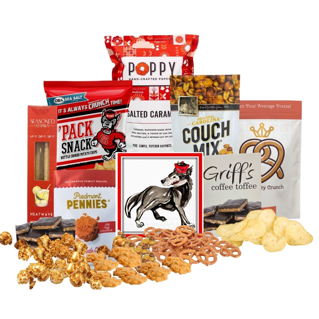 NC State-themed gift basket contents arranged on a countertop with small piles of each snack in front, showcasing red-packaged North Carolina-made gourmet treats