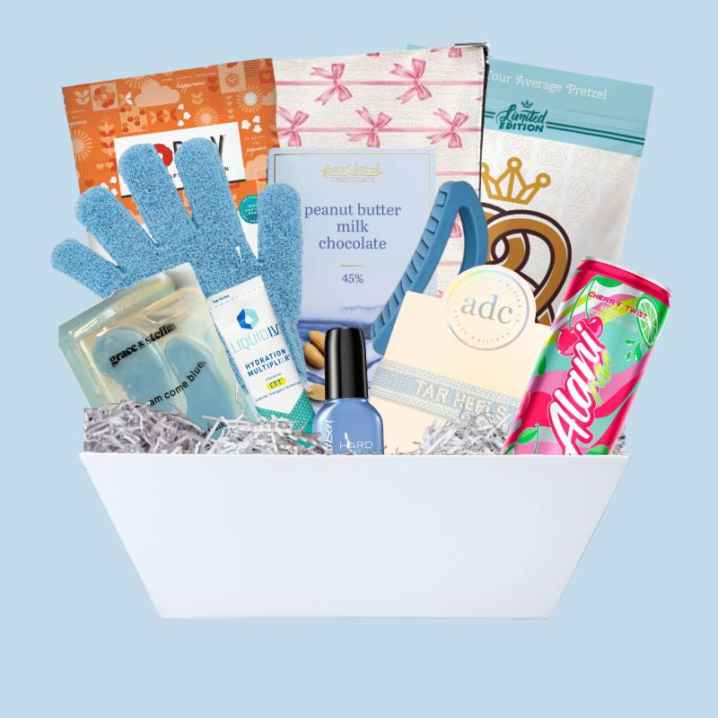 UNC Chapel Hill gift basket full of Carolina blue gifts for girls who enjoy self care, including a Tar Heels game day bracelet, UNC chocolates, cosmetic items, and made in North Carolina snacks
