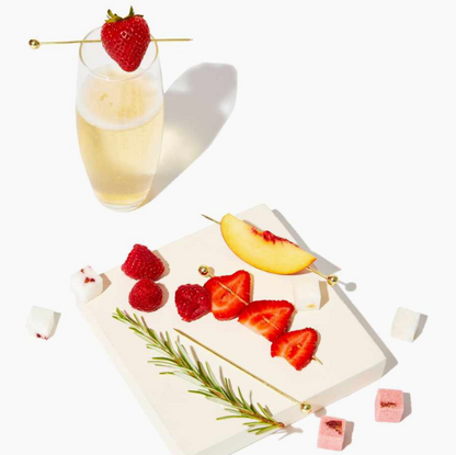 Elegant lifestyle image of fresh strawberries speared on gold cocktail picks resting on a champagne glass, highlighting the stylish bar accessories included in the Men’s Old Fashioned Gift Box.