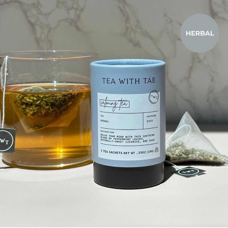 Tea with Tae herbal tea packaging with a glass of tea and loose tea leaves on a marble background