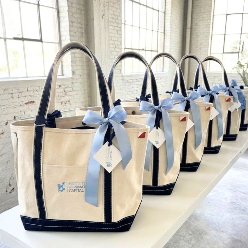 Bulk corporate welcome gift totes with navy trim and blue ribbons staged for a North Carolina client event