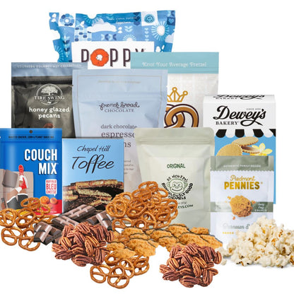 Winter Luxe Gourmet gift basket contents displayed on a kitchen counter  with North Carolina artisan snacks, popcorn, pretzels, chocolate, toffee, coffee, and hot chocolate arranged neatly with piles of each treat in front of its packaging.