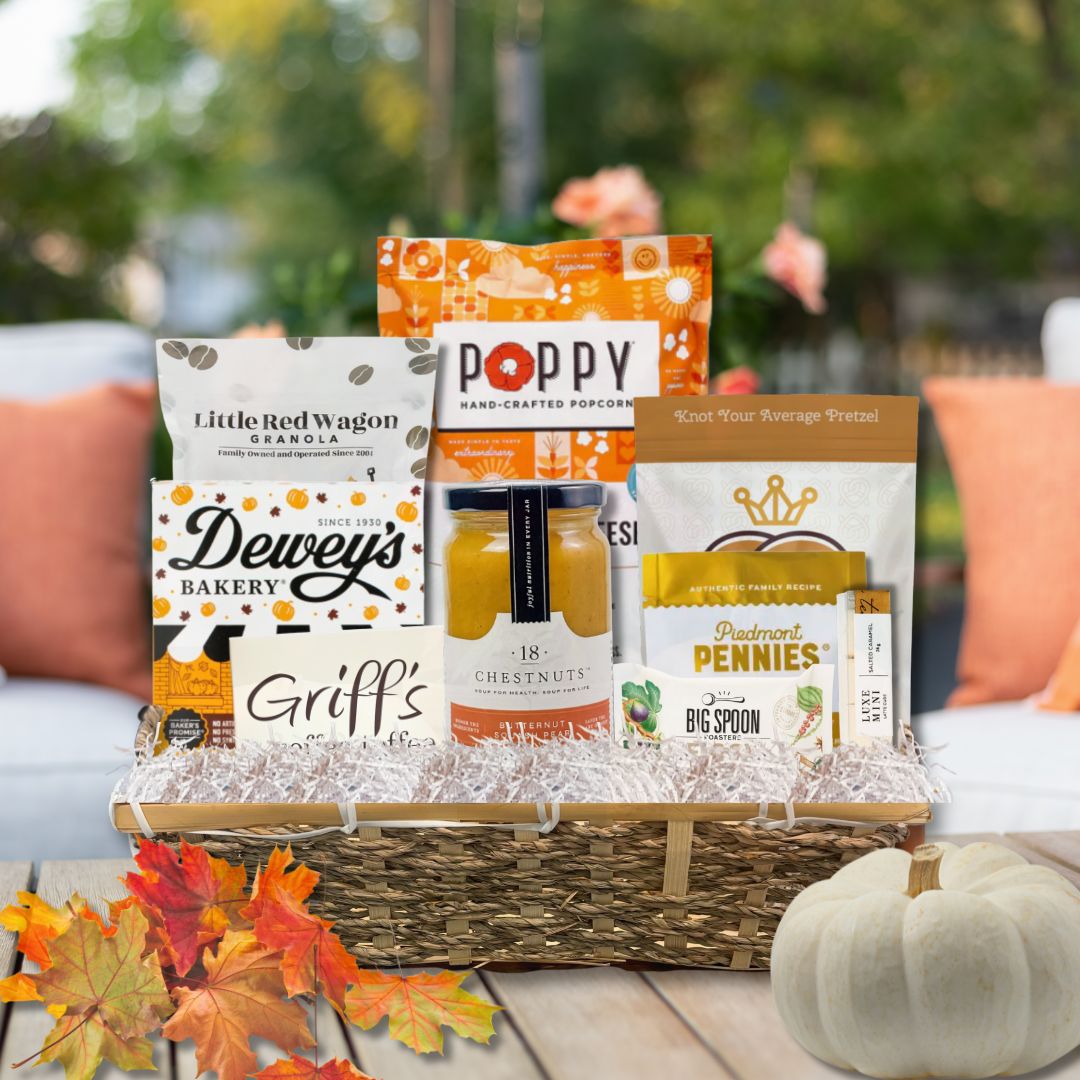 Elegant fall-themed gourmet gift basket filled with North Carolina-made snacks and treats, displayed against a cozy autumn backdrop with seasonal decor and warm tones