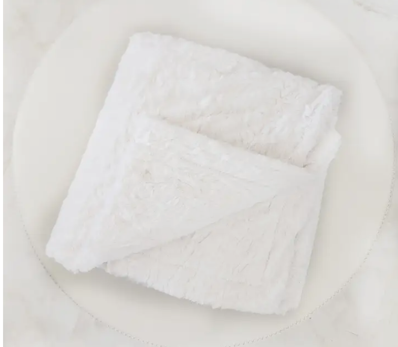 A plush faux fur lap blanket neatly folded to show its soft texture and reversible design—perfect for cozy gifting or relaxing at home.