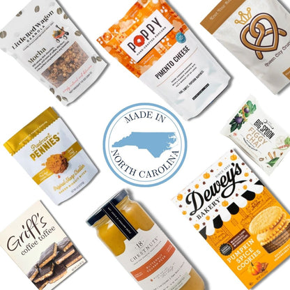 Flat lay of North Carolina-made gourmet products including snacks, soup, and treats, arranged around a central "Made in North Carolina" badge for a local gift basket collection