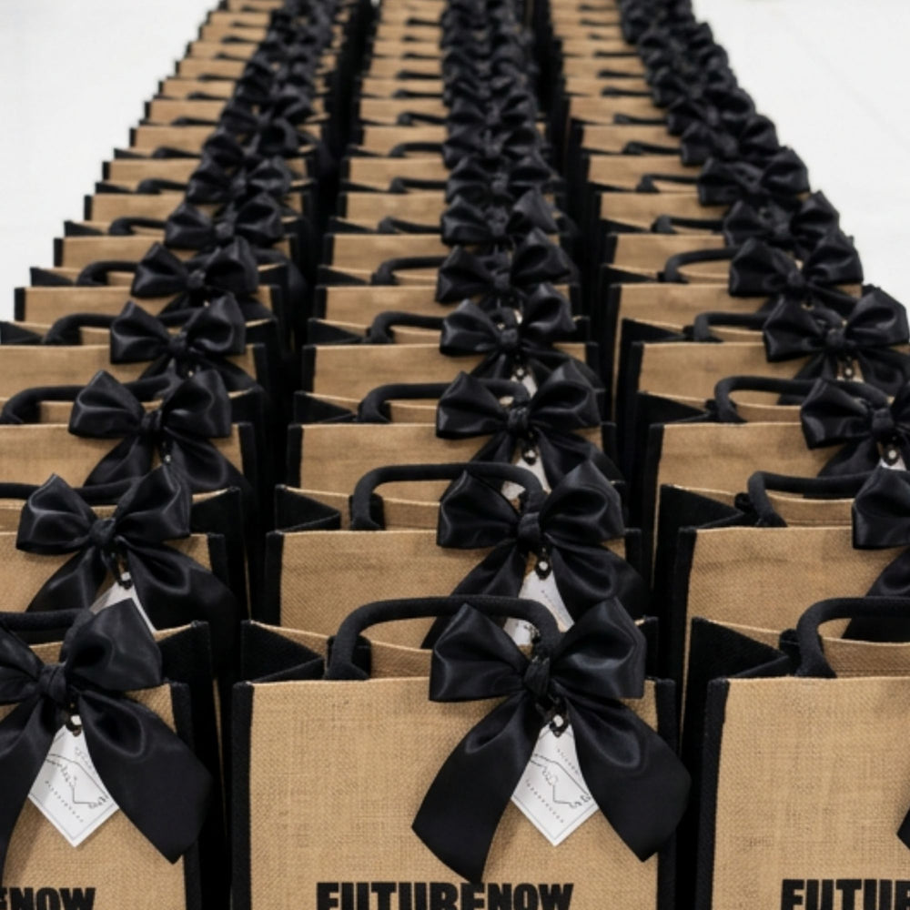 Rows of custom branded corporate welcome bags with black ribbons staged for a bulk client order