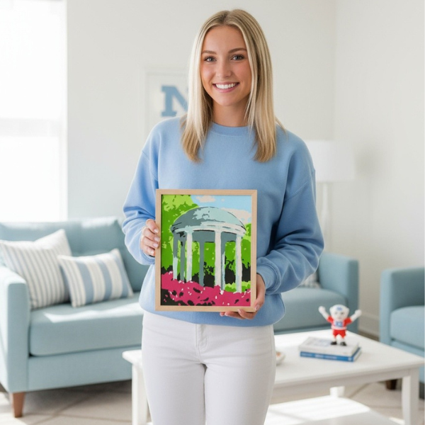UNC Chapel Hill student holding the completed painting of the Old well that is made by using this paint by number kit.