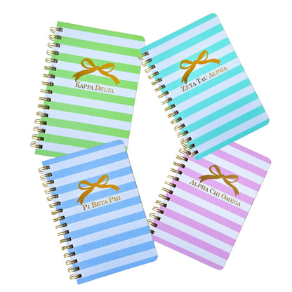 Spiral sorority notebook with gold bow design and sorority letters in sorority colors