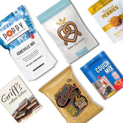 Flat lay of the Carolina Snack Box contents including NC-made popcorn, chips, granola, cookies, toffee, and snack mix, arranged neatly on a white background
