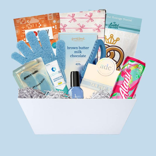 UNC Chapel Hill gift basket full of Carolina blue gifts for girls who enjoy self care, including a Tar Heels game day bracelet, UNC chocolates, cosmetic items, and made in North Carolina snacks
