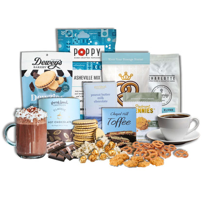 Winter Luxe Gourmet gift basket contents displayed on a kitchen counter  with North Carolina artisan snacks, popcorn, pretzels, chocolate, toffee, coffee, and hot chocolate arranged neatly with piles of each treat in front of its packaging.